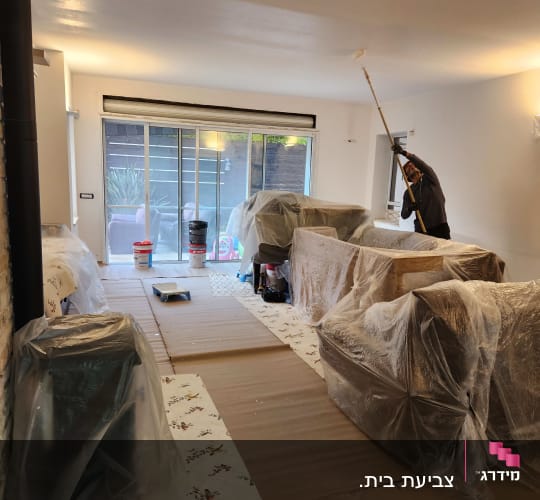 אדם צובע תקרה עם רולר על מוט ארוך